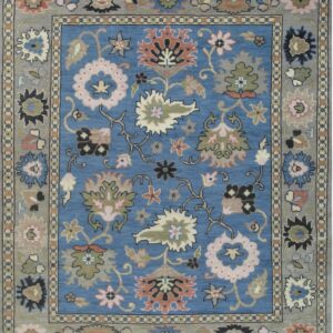 Blue and gray rug featuring a stylized floral pattern in pink, green, and coral accents.
