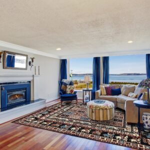 A traditional dark rug with complex red, blue, and cream patterns grounds a room with a tan couch and scenic view.
