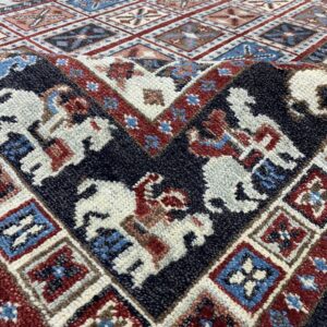 Textured rug detail with geometric diamonds and figures in dark blue, cream, rust, and light blue.