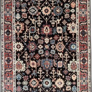 Dark pile rug with a dense, traditional pattern in red, navy, cream, and peach colors on a black field.