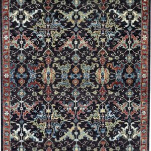 A dark navy, low-pile rug featuring intricate traditional motifs in red, teal, gold, and cream.