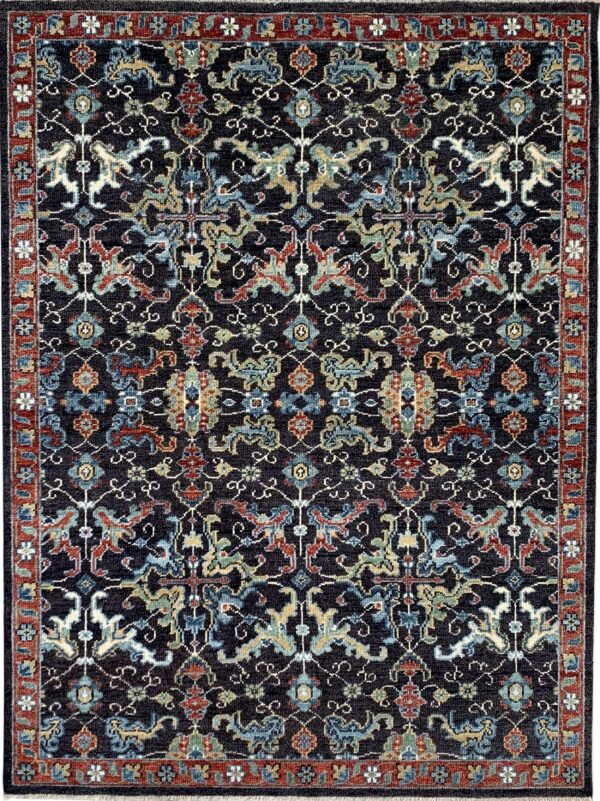 A dark navy, low-pile rug featuring intricate traditional motifs in red, teal, gold, and cream.
