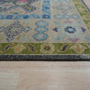 Gray, blue, and pink patchwork rug with a chunky pile and lime green border on blonde flooring.