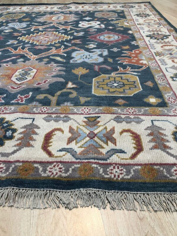 Medium-pile rug featuring a deep blue field and ivory border with multicolored tribal designs resting on light wood floors.