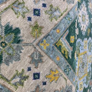 Detailed view of a textured rug featuring traditional beige, forest green, blue, and yellow geometric patterns.