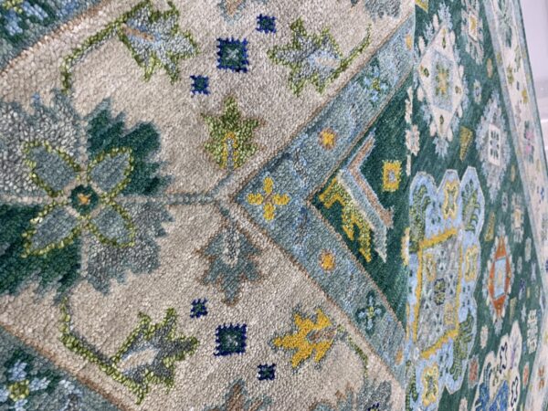 Detailed view of a textured rug featuring traditional beige, forest green, blue, and yellow geometric patterns.