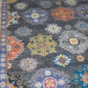 Textured gray rug with colorful scattered floral medallions and a detailed blue and yellow patterned border.