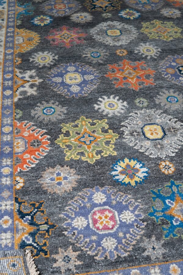 Textured gray rug with colorful scattered floral medallions and a detailed blue and yellow patterned border.