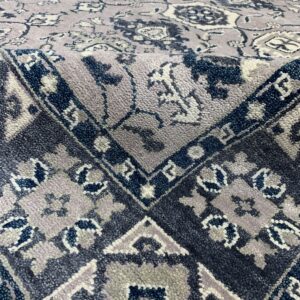 High-pile area rug with detailed floral field and geometric border in navy, purple, and gray.