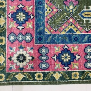 Detailed traditional rug corner with pink, blue, green, and yellow geometric patterns resting on a white tiled floor.