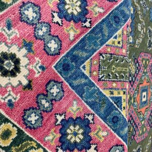 Vibrant high-pile rug with complex geometric patterns in fuchsia, blue, green, and cream colors.