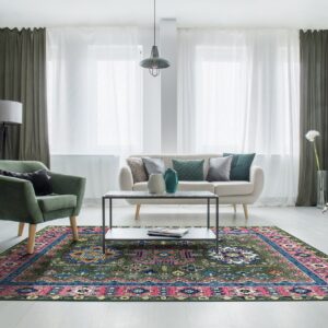 A dark green traditional rug featuring pink and blue accents sits on light wood flooring in a living room.