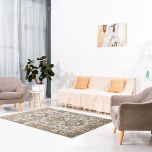 An intricate, traditional rug in rust and gray tones rests on glossy white flooring between modern chairs.