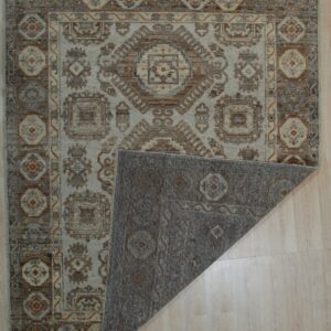 Beige and brown traditional area rug on a light floor, showing the gray patterned backing folded over.