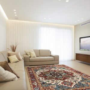 A detailed red, blue, and cream traditional area rug grounds a modern living space with tan leather seating.