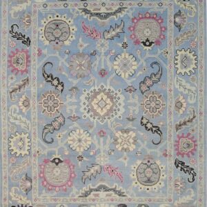 Ornate traditional rug with a light blue field and dense floral motifs in pink, gray, and cream.