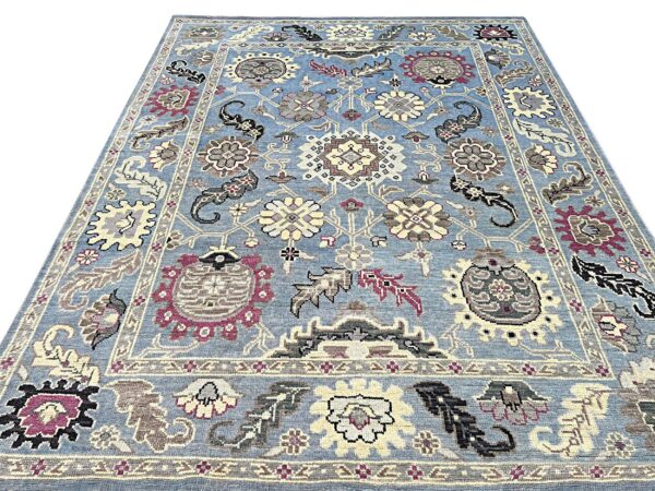 Light blue traditional rug featuring dense cream, gray, and burgundy floral medallions and border designs.