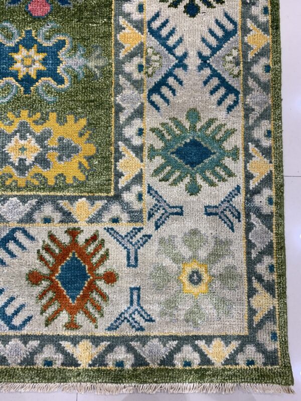 A textured rug with tribal geometric patterns in green, light gray, blue, yellow, and rust colors.