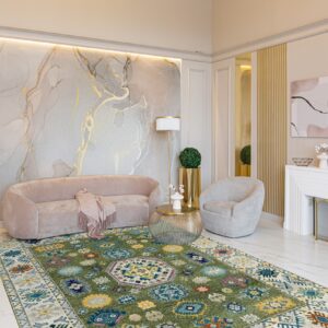 Geometric green rug under a curved pink sofa and gold decor on white marble flooring.