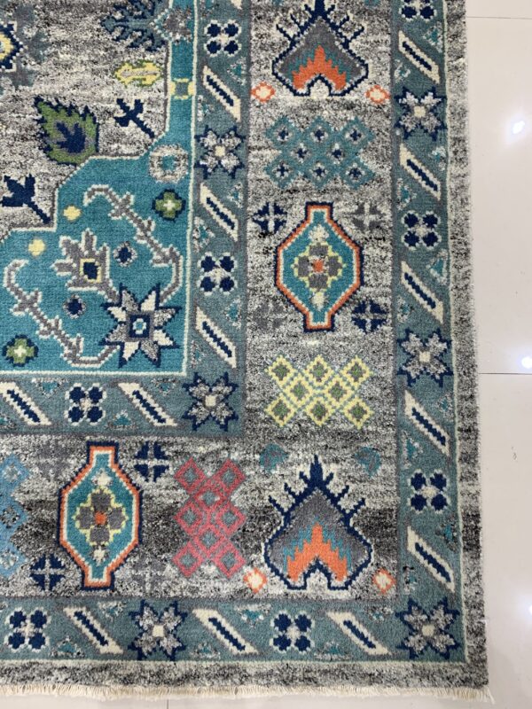 Distressed geometric rug corner showing blue, teal, orange, and gray patterns resting on white tile flooring.