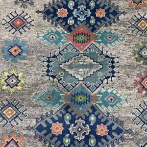 Textured rug with tribal geometric patterns in navy, teal, orange, and yellow on a distressed gray field.