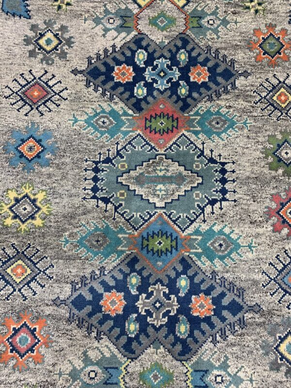 Textured rug with tribal geometric patterns in navy, teal, orange, and yellow on a distressed gray field.