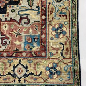 Detailed view of a low-pile rug with geometric patterns in beige, blue, red, and dark navy on a white floor.