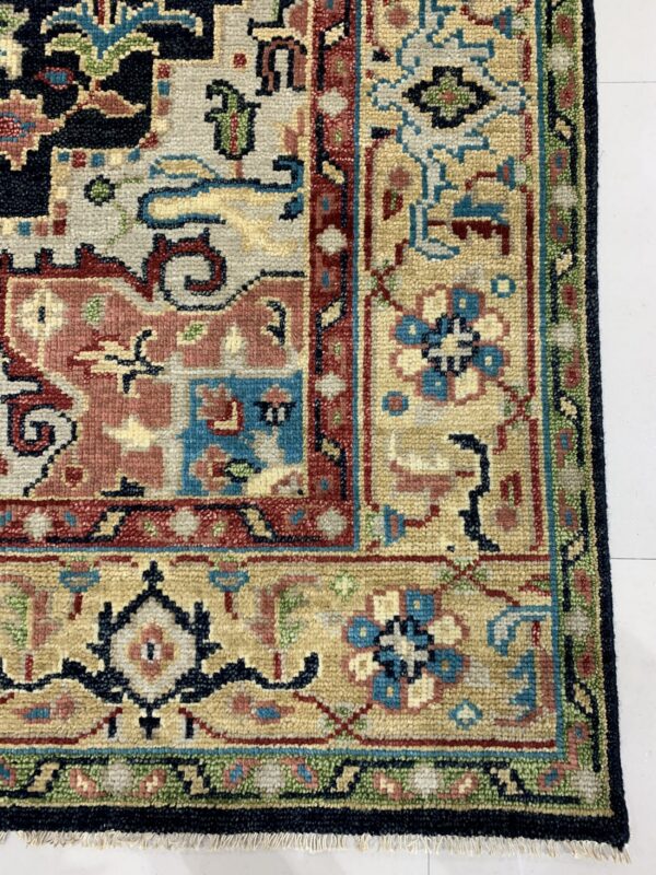 Detailed view of a low-pile rug with geometric patterns in beige, blue, red, and dark navy on a white floor.