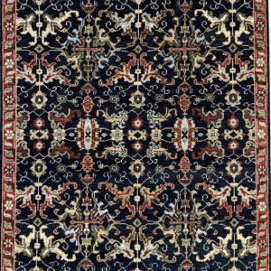 Dark blue traditional low-pile rug with intricate multicolored patterns and a prominent red floral border.