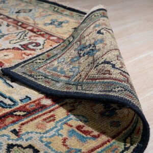 A multicolored traditional patterned rug is curled back, revealing the intricate backing on light wood floors.