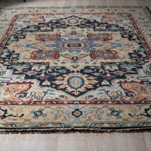 A geometric traditional rug featuring cream, navy, terracotta, and blue colors on light wood floors.