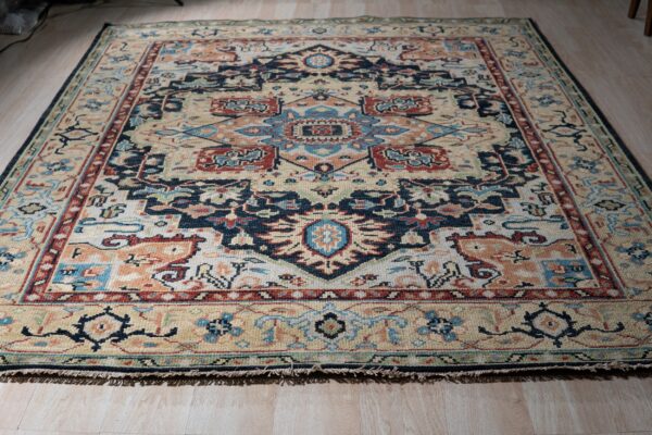 A geometric traditional rug featuring cream, navy, terracotta, and blue colors on light wood floors.