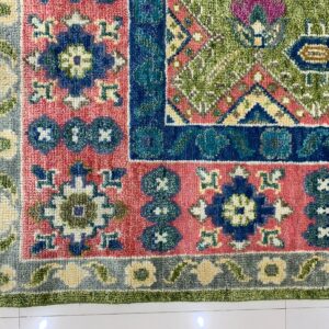 High-pile rug corner showing vivid geometric designs in pink, blue, lime green, and teal on white tile.