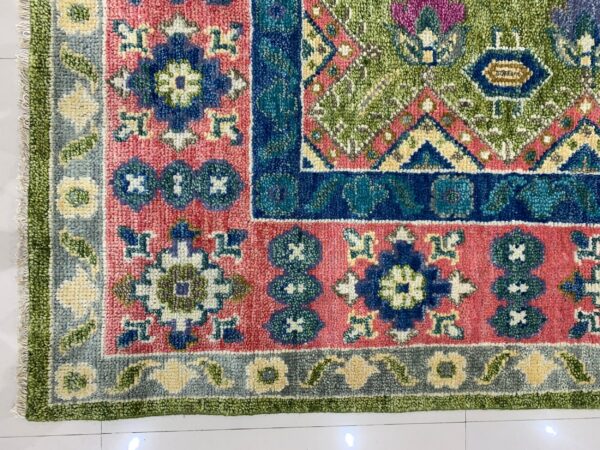 High-pile rug corner showing vivid geometric designs in pink, blue, lime green, and teal on white tile.