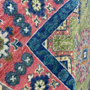 High-pile rug featuring bold geometric patterns in contrasting pink, royal blue, and olive green.