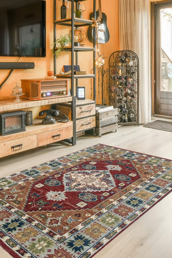 A traditional rug with red, blue, and brown geometric patterns sits on light wood flooring.