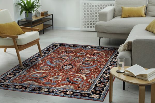 Rust-colored traditional pattern rug grounds a bright room with light gray seating and wood furniture.