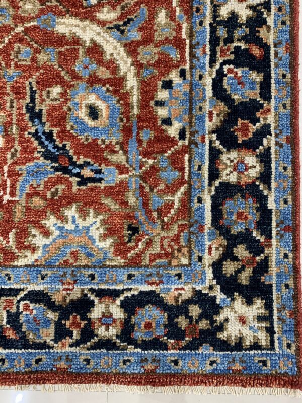 Textured, high-pile rug featuring intricate traditional designs in red, navy, tan, and sky blue colors.