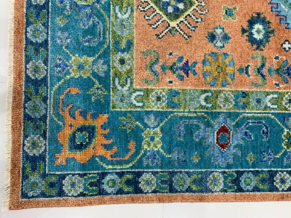 Traditional high-pile rug corner with teal, peach, and dark blue floral and geometric patterns.