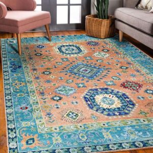 A salmon and blue patterned rug covers wood flooring between two upholstered armchairs.