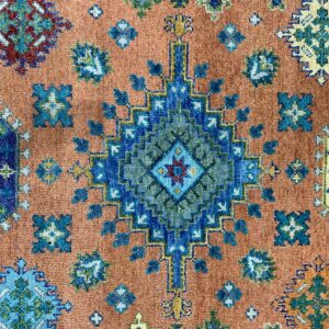 Geometric blue and green medallion design on a field of rusty orange with a low, dense pile.