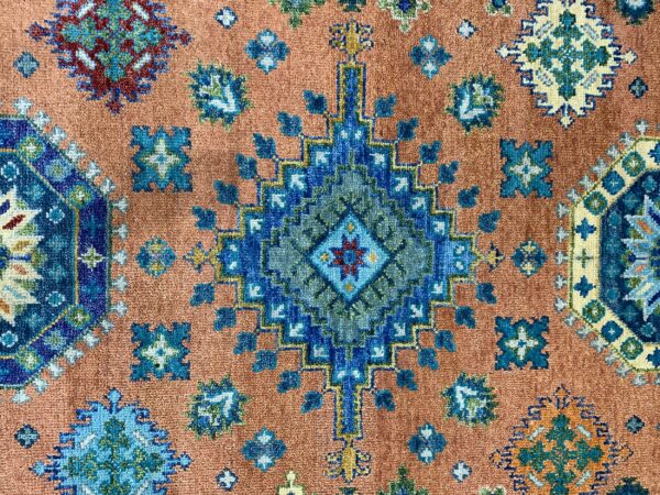 Geometric blue and green medallion design on a field of rusty orange with a low, dense pile.