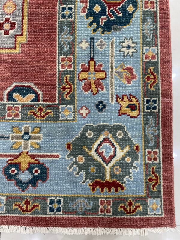 This rug detail shows intricate traditional patterns in red, sky blue, and slate gray on white tile.