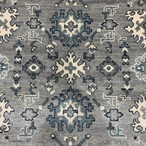 A dense, low-pile gray rug detailed with traditional geometric patterns in blue and ivory.