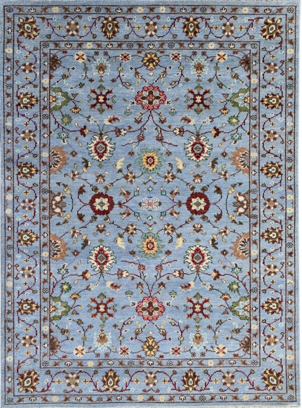 Traditional light blue rug with an all-over intricate floral design in maroon, tan, green, and pink.
