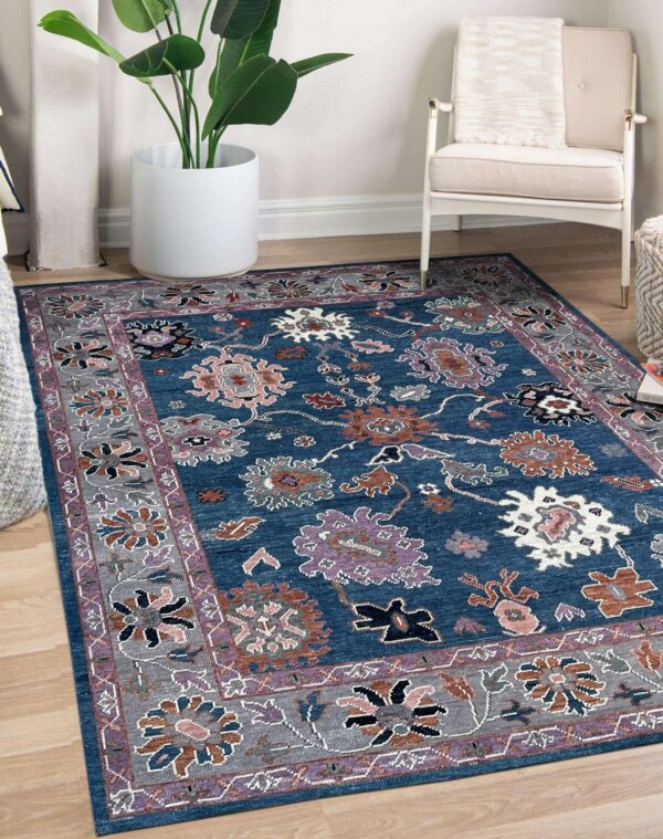 Blue traditional rug featuring gray and purple borders and multi-colored floral patterns on wood floor.