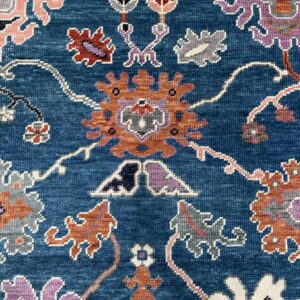Textured, deep blue rug detail showing stylized flowers in orange, lavender, pink, and white.