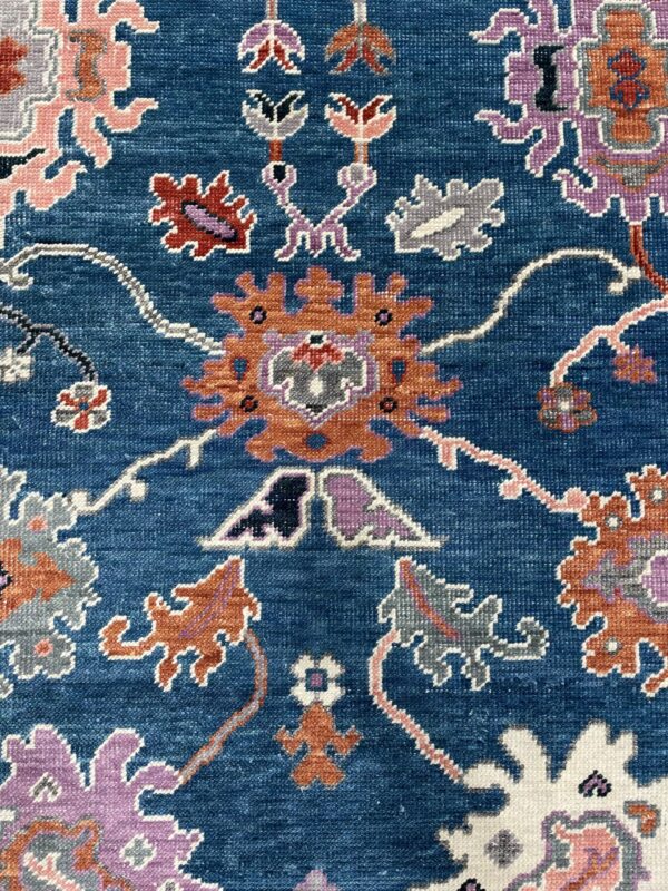 Textured, deep blue rug detail showing stylized flowers in orange, lavender, pink, and white.
