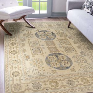 Cream traditional geometric rug with tan and slate blue accents under a white chair and gray sofa.