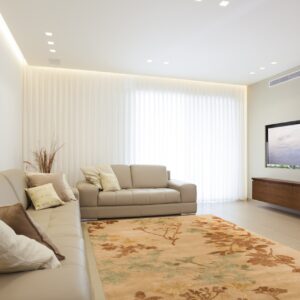 Tan floral rug with rust and gold botanicals on light tiled floor under modern beige sectional seating.